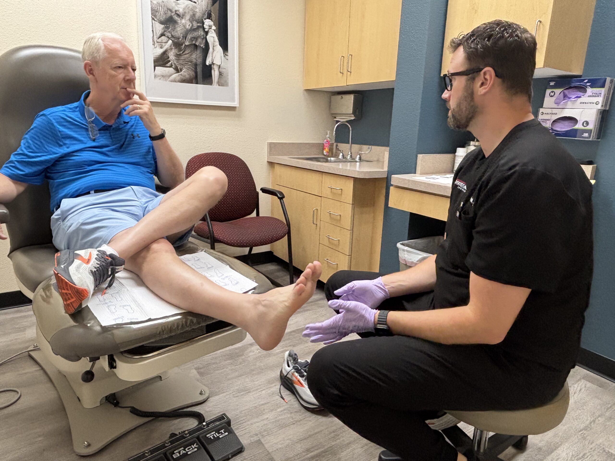 Podiatrist examining a patient’s ankle for Achilles tendon pain during a clinical visit at Preferred Foot & Ankle Specialists in Chandler, Arizona.